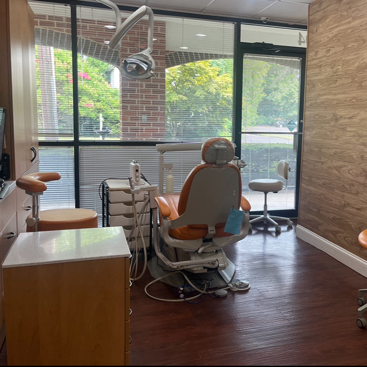 The image shows a dental office interior with dental chairs, a reception desk, and equipment.