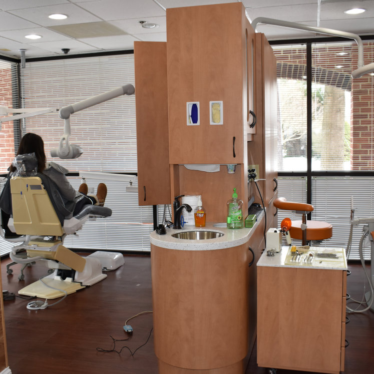 The image shows an interior space of a dental office, featuring dental chairs, equipment, and a reception area.