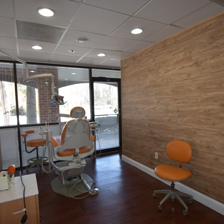 The image shows an interior of a dental office with modern furnishings, including chairs and equipment.