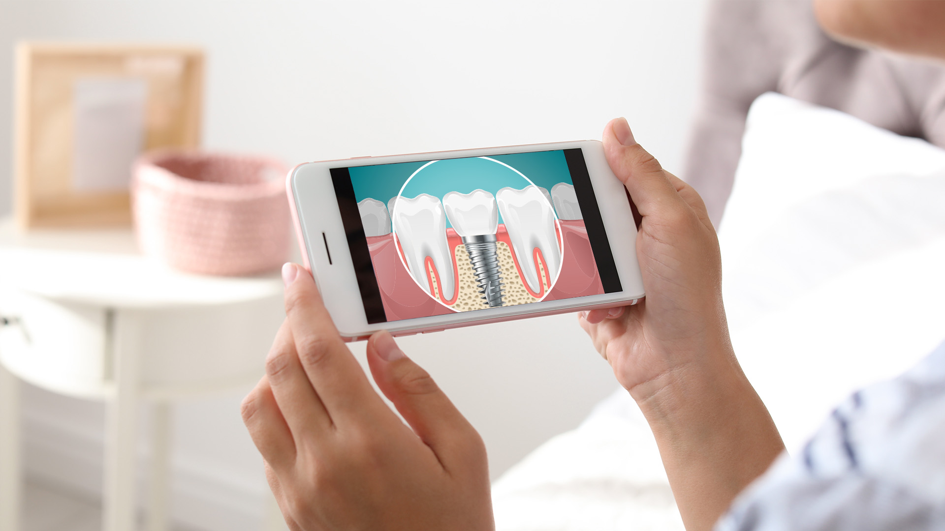 A person holding a smartphone displaying an illustration of a tooth with a crack and an overlay of a magnified view showing the internal structure of a tooth.