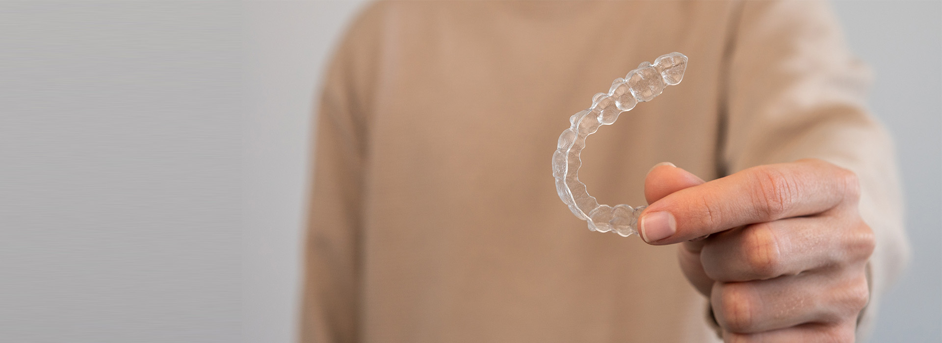 The image shows a person s hand holding a transparent soap bubble against a white background, with the focus on the bubble.