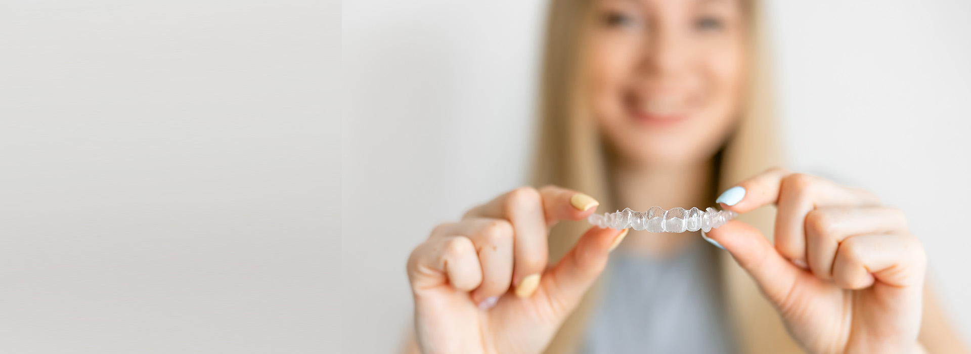 A woman is holding a ring in her hands, showcasing it against a plain background.