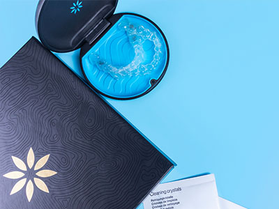 A black and white book with a blue toothbrush and a small container of dental floss on a light blue background.