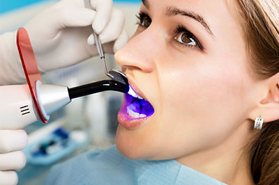 A woman receiving dental treatment, with a dentist using a device to clean her teeth.