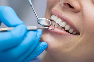 The image shows a person receiving dental care, with a dental professional using a tool to work on their teeth.