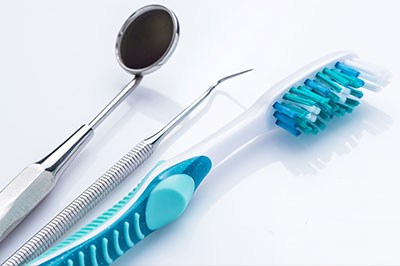 A collection of dental tools, including a toothbrush with blue bristles and a pair of scissors, arranged on a white background.