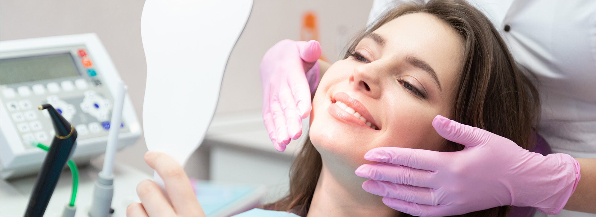 A woman receiving dental care with a dentist using a magnifying glass.