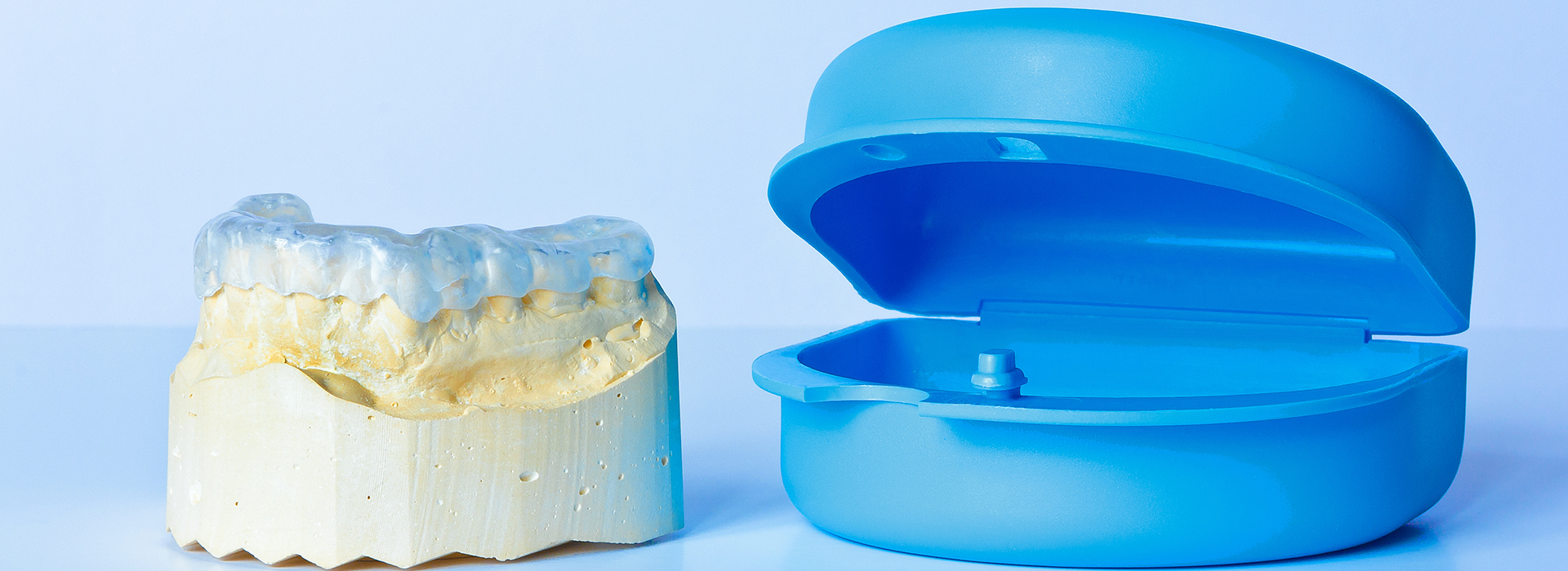 The image shows a blue dental impression tray and a yellow tooth model placed side by side against a white background.