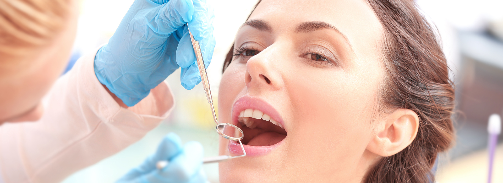 A dental professional performing a dental procedure, with the patient s mouth open and a dental drill in use.