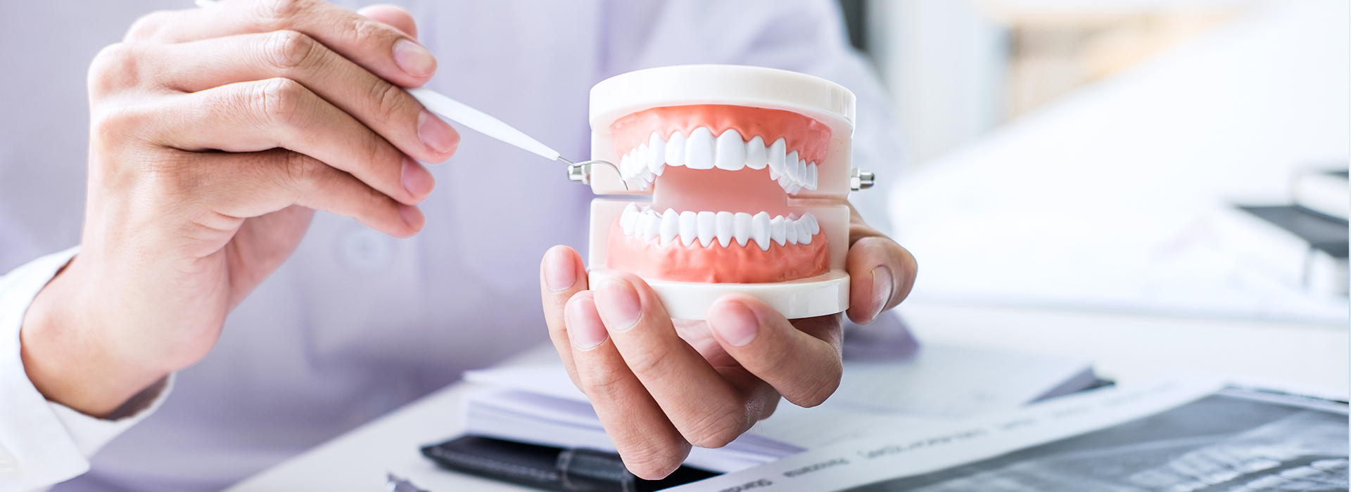 A person s hand holding a white cup with a toothbrush and toothpaste, while another hand is writing on a piece of paper.