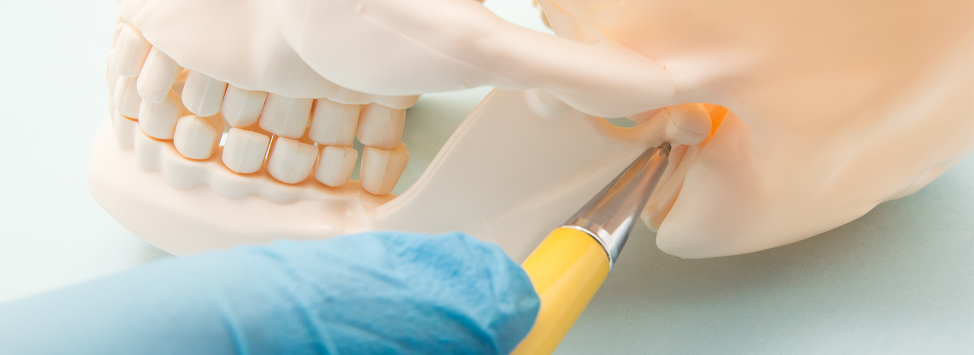 The image shows a close-up of a person s face with a focus on the dental area, where a tooth is being extracted by a dentist using tools and a dental dam.