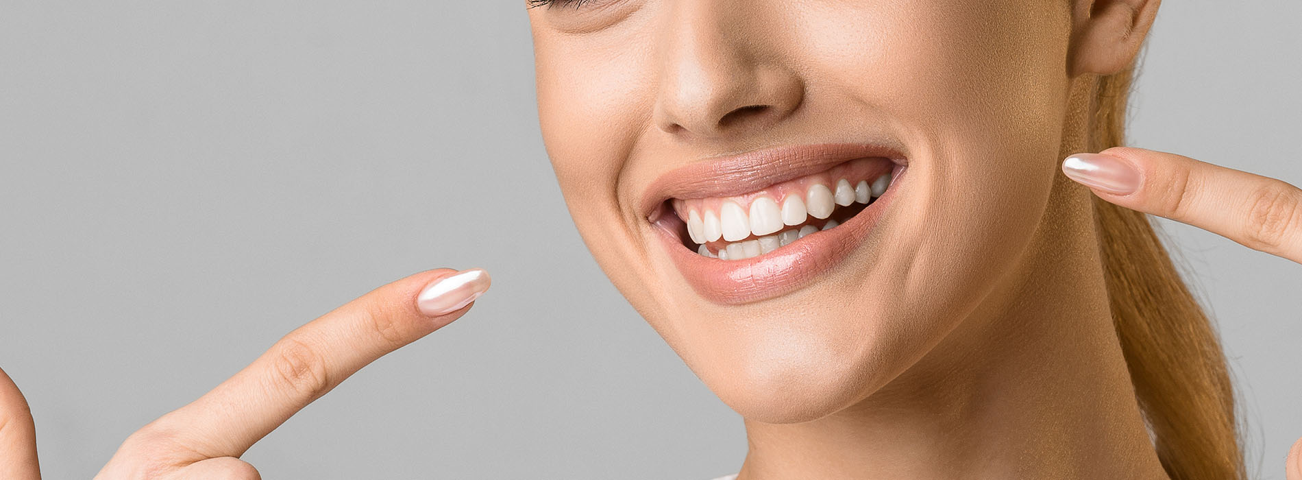 The image shows a smiling woman with her eyes closed, displaying a joyful expression while holding up her index finger and thumb.