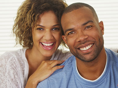 Two adults, a man and a woman, smiling and posing closely together in a photograph.