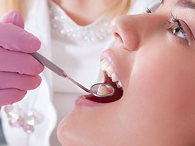 A woman receiving dental care, with a dentist using a drill on her teeth.