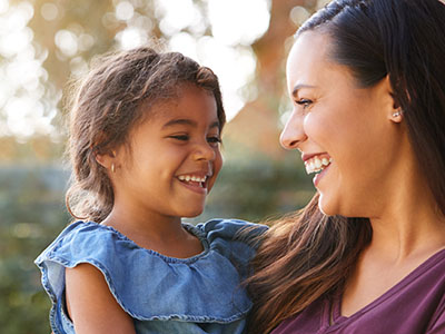 A woman and a child are smiling at the camera, with the woman holding the child.