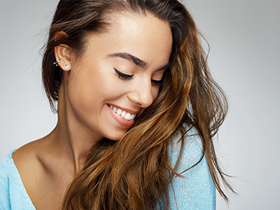 A woman with a radiant smile, long hair, and a blue top.