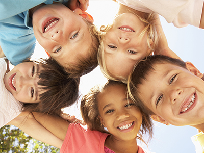 The image shows a group of children smiling and posing for the camera.