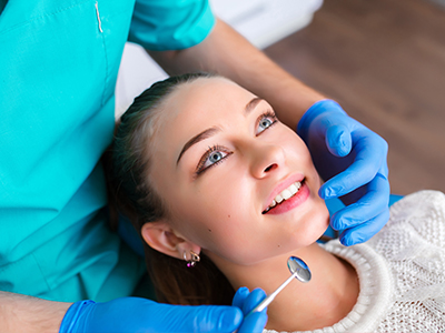 A young woman receiving dental care, with a dentist performing a procedure on her mouth.